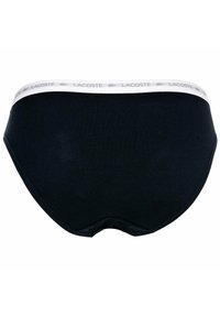 Mutande nere in cotone con una cintura elastica bianca che presenta il nome del marchio "Lacoste" stampato. Design semplice con una texture liscia.