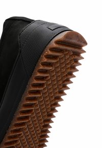 Sneaker alta in suede nero con accenti in gomma testurizzata, caratterizzata da una suola rigata marrone e un battistrada a motivo a rombi per una migliore aderenza.