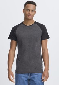 Camiseta de manga corta en gris oscuro con mangas raglán negras. Fabricada en algodón suave, presenta un cuello redondo y un ajuste casual.