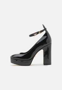 Scarpe con tacco alto in vernice nera, con piattaforma, cinturino alla caviglia e dettagli in metallo dorato. Punta arrotondata e superficie lucida.