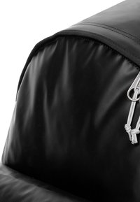 Sac en tissu noir au design épuré, avec une surface texturée, des fermetures éclair en métal argenté et un cordon de serrage.