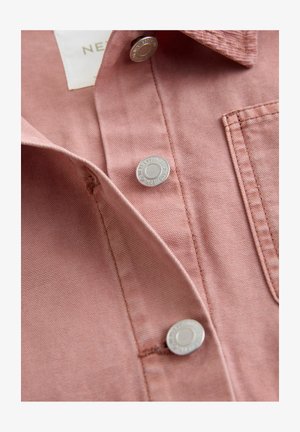 Rosenfarbenes Hemd aus strukturiertem Stoff, mit silbernen Druckknöpfen und einer Brusttasche. Der Kragen ist umgeschlagen und zeigt Nahtdetails.