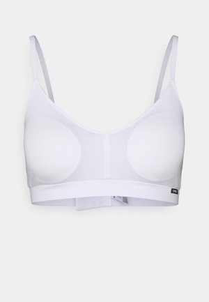White bralette made of stretchy fabric, featuring two circular padded cups, thin adjustable straps, and a wide band around the bottom.