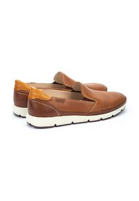 Zapatos de piel marrón sin cordones con parte superior perforada, suela de goma crema y acentos en contraste en tono marrón claro en el talón y el cuello.