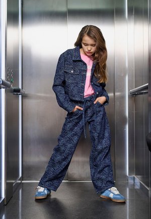 Navy denim outfit featuring floral pattern, cropped jacket, loose pants with a tied waist, and blue sneakers with white accents.