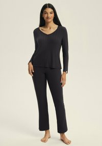 Dark gray ribbed pajama set with long sleeves, v-neckline, and straight-leg pants, featuring a soft texture and minimalistic design.