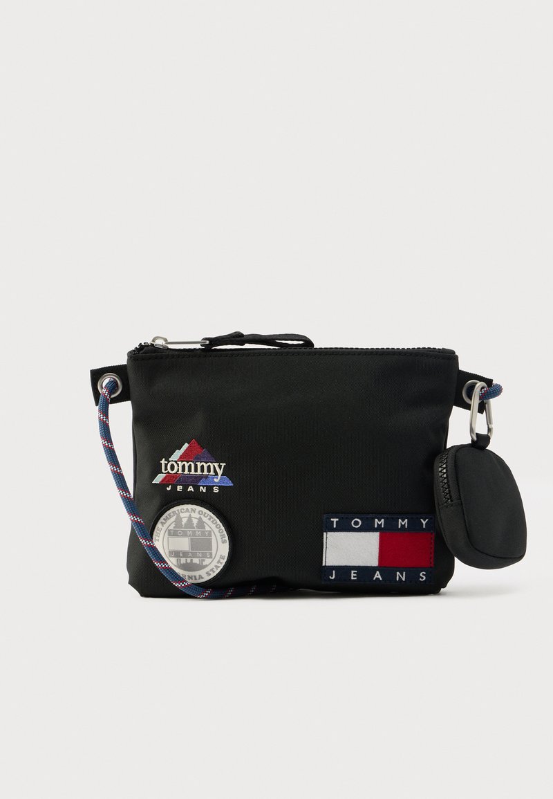 Musta nailoninen vetoketjullinen pussukka, jossa on useita punaisen, valkoisen ja sinisen värisiä merkkejä ja koristeita. Mukana irrotettava avainketju.