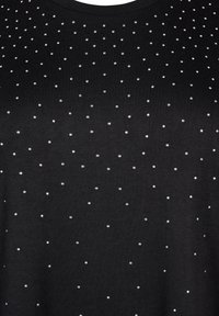 Tessuto nero con piccole borchie in argento disposte in modo uniforme che formano un motivo sottile sulla superficie.