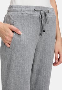 Szare, w paski spodnie dresowe z elastycznym paskiem i sznurkiem do regulacji. Posiadają boczne kieszenie i teksturowany materiał zapewniający komfort.