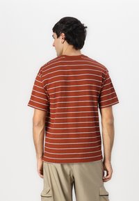 Brunstribet t-shirt med korte ærmer, en rund halsudskæring og en afslappet pasform, parret med khaki cargo shorts.
