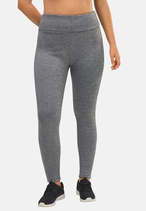Mallas deportivas grises con una cintura alta, fabricadas en tejido elástico, diseño ajustado y textura suave, combinadas con zapatillas deportivas negras.