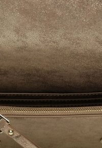 Borsa in suede marrone con una finitura testurizzata, dotata di una tasca con zip, accenti di cucitura e una tracolla rimovibile.