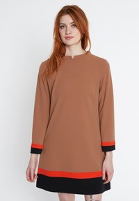Braunes, langärmliges Kleid mit rundem Ausschnitt, das rote und schwarze horizontale Akzente an den Ärmeln und am Saum aufweist. Glatte Stofftextur.