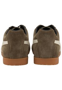 Sneaker in suede marrone con una striscia in pelle bianca, tacco arrotondato e suola in gomma. Il materiale superiore testurizzato e i colori a contrasto aumentano l'appeal visivo.