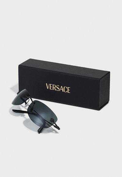Sunglasses with dark lenses, black frames, and a round shape. Presented with a black Versace box featuring gold lettering.