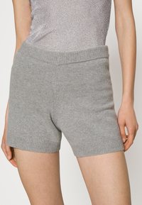 Shorts en tricot gris avec une large taille élastique et des ourlets côtelés, affichant une texture douce et un design ajusté.