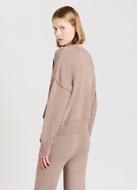 Maglione a maglia testurizzato di colore marrone chiaro, con una vestibilità morbida, polsini e orlo ribattuti. La vista posteriore mostra un ampio scollo rotondo e spalle basse.