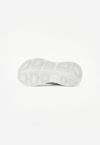 Semelle de sneaker blanche en caoutchouc texturé, présentant des rainures multidirectionnelles et des sections surélevées pour une traction optimale. Design minimaliste, sans marque visible.