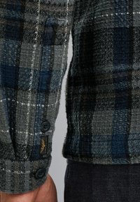 Grijs en blauwe geruite flanellen shirt met gestructureerde stof, knopenmanchetten en een subtiele logo-label op de mouw. Tailored fit met contrasterende patronen.