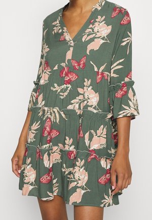 Grøn blomsterkjole med sommerfuglemønstre, flæseærmer og lagdelt design. Fremstillet af blødt stof med nuancer af pink og creme.