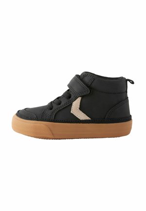 Bottines noires à tige haute avec une semelle en caoutchouc, dotées d'une sangle en Velcro, de lacets noirs et d'une touche de beige sur le côté. Texture lisse.