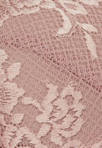 Roze kantstof met een bloemmotief, voorzien van intrigerende borduurdetails en een delicate, lichte textuur.