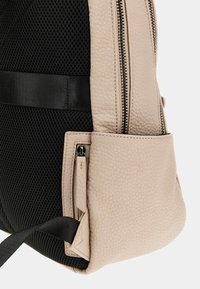 Zaino in pelle beige con superficie texture, pannello in mesh nero e tasca con zip. Caratterizzato da una cinghia resistente e un design elegante.