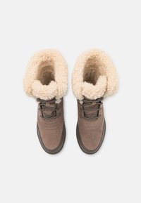 Een paar bruine winterlaarzen met een dikke beige fleece voering en zwarte veters, van bovenaf bekeken op een witte achtergrond.