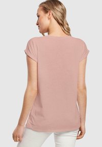 Helles rosa Kurzarm-T-Shirt, weicher Stoff, lässiger Schnitt, runder Halsausschnitt und umgeschlagene Ärmel. Nahtdetail entlang des Rückens.