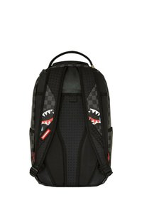 Zaino nero con motivo a scacchi, forma arrotondata, schienale imbottito e design di denti di squalo rossi e bianchi sulle spalline.