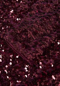 Bourgondische stof bedekt met glanzende, ronde pailletten, met een zachte textuur en een gladde afwerking, die een opvallend fonkelend effect creëert.