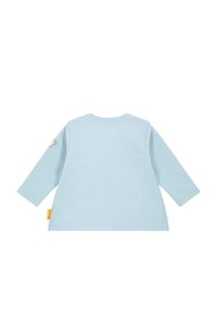 Helles blaues Langarm-T-Shirt für Kleinkinder mit rundem Hals, kleinem Teddybär-Patch am linken Ärmel und gelbem Markenetikett an der unteren Seitennaht.