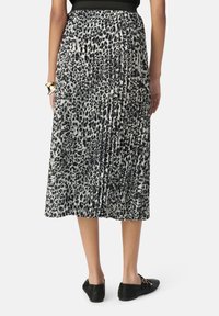 Falda midi plisada en un estampado de leopardo en blanco y negro. Hecha de una tela ligera, presenta una cintura elástica y una superficie texturizada.