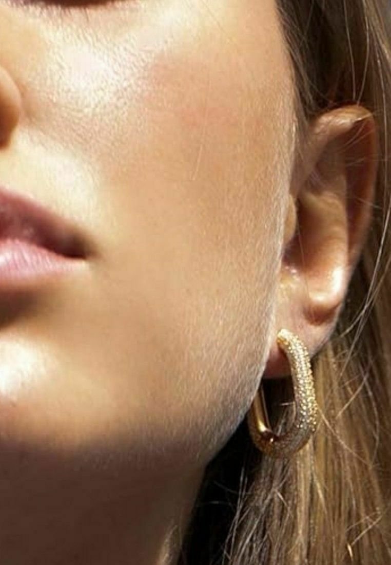 Guld hoopörhänge med en texturerad yta som har en delikat glans. Örhänget är runt med en polerad yta som framhäver dess design.