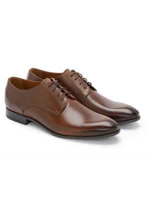 Brązowe skórzane buty eleganckie z gładkim wykończeniem, okrągłym noskiem oraz sześcioma parami otworów na sznurowadła. Czarna gumowa podeszwa z delikatnym obcasem.