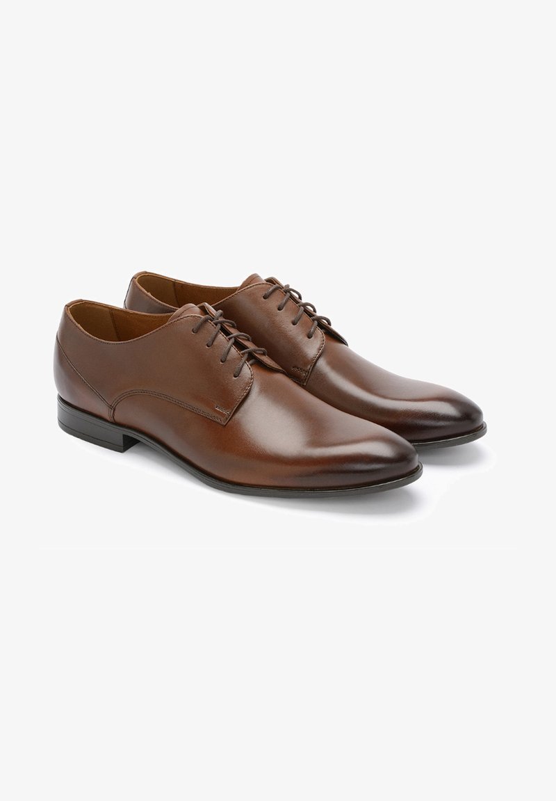 Brązowe skórzane buty eleganckie z gładkim wykończeniem, okrągłym noskiem oraz sześcioma parami otworów na sznurowadła. Czarna gumowa podeszwa z delikatnym obcasem.