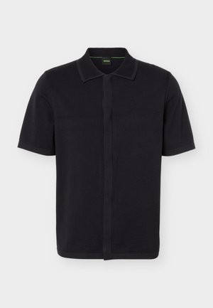 Polo noir à manches courtes avec col côtelé, patte de boutonnage cachée et texture subtile sur la couture latérale, orné d'un petit logo embossé.