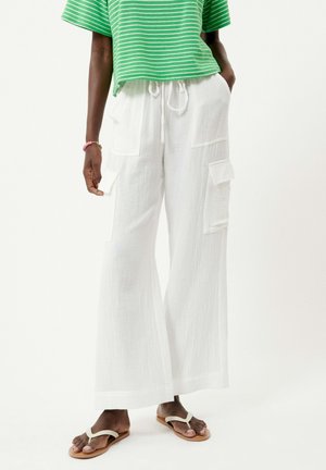 Witte wijde cargobroek met textuurstof, zijzakken en een trekkoord in de taille. Gekoeld met een groen gestreept crop top en sandalen.