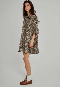 Kurzkleid mit Leopardenmuster, kragenlosen Ausschnitt, kurzen Ärmeln und A-Linien-Form. Hergestellt aus leichtem Stoff mit glatter Textur.