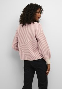 Gestreepte pullovertrui in lichtroze en beige, met een ontspannen pasvorm, ronde hals en geribbelde manchetten. Zachte textuur met diagonale streepdetails.