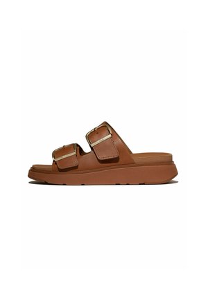 Bruine slidesandalen met twee verstelbare gespsluitingen en een dikke zool, afgebeeld in zijaanzicht op een witte achtergrond.