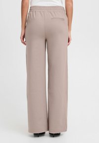 Spodnie wide-leg w miękkim taupe. Posiadają elastyczny pas i jedną tylną kieszeń. Gładka faktura z minimalnymi detalami.