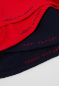 Tričko z bavlny, stohované; jedno červené, dve námornícke modré s červeným textom "TOMMY HILFIGER" výrazne zobrazeným na látke.