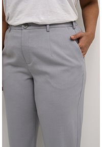 Pantalones gris claro confeccionados en una tela suave, con un diseño de pierna recta, bolsillos laterales y cierre de botón en la cintura.