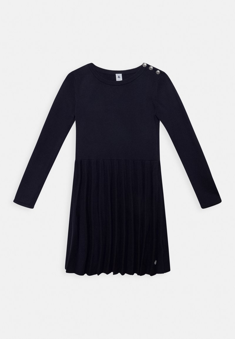 Robe noire à manches longues avec jupe plissée, col rond et trois boutons argentés sur l'épaule gauche.