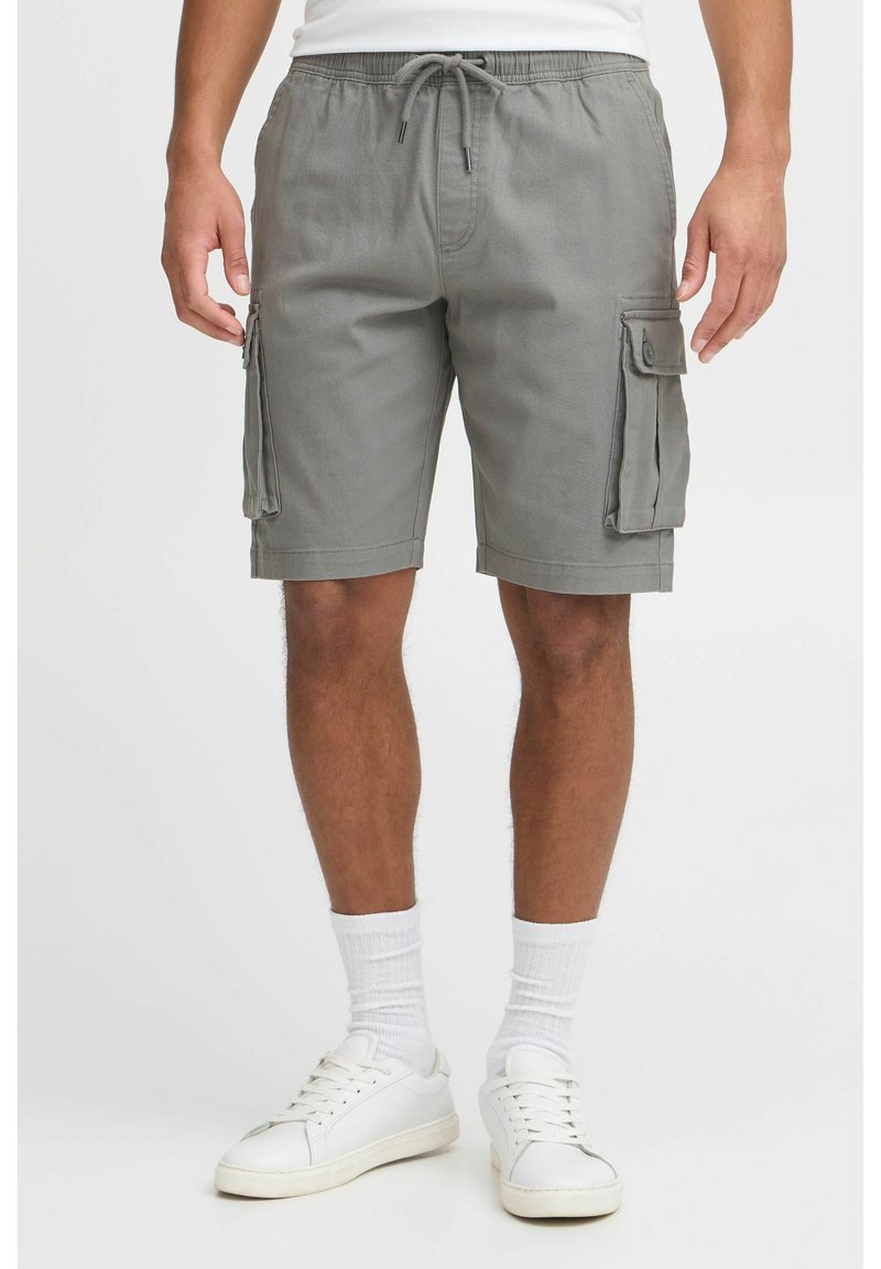 Graue Cargo-Shorts aus Baumwollmischung, mit zwei Seitentaschen, einem Kordelzugbund und einem lässigen Schnitt, kombiniert mit weißen Sneakers und Socken.