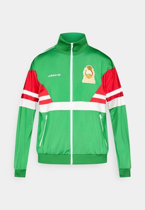 Green track jacket with red sleeves and white horizontal stripes. Features a zip closure, high collar, embroidered logo, and elastic cuffs.