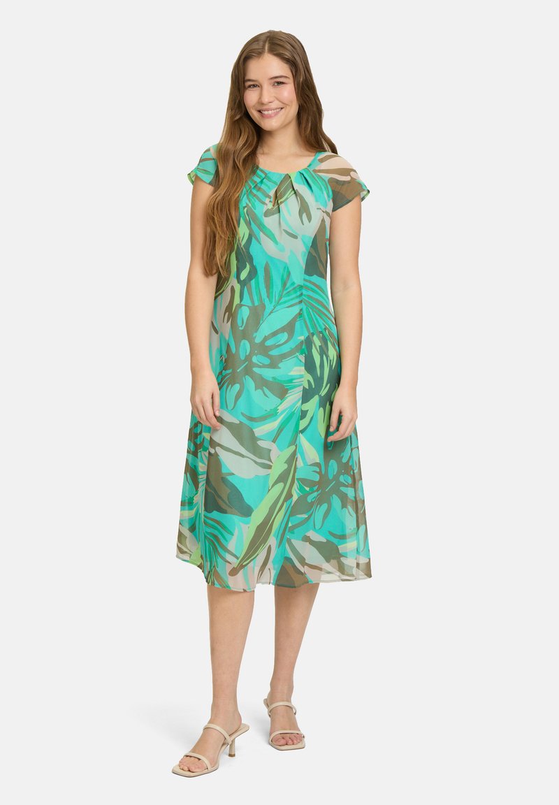 Sukienka do kolan, krótki rękaw w kolorze turkusowym i zielonym z wzorem liści, z okrągłym dekoltem i zwiewnym materiałem.
