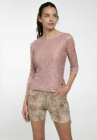 Spitzenoberteil in staubigem Rosaton, mit langen Ärmeln und floralen Mustern, kombiniert mit hellbraunen, leicht verwaschenen Shorts mit Stickerei.
