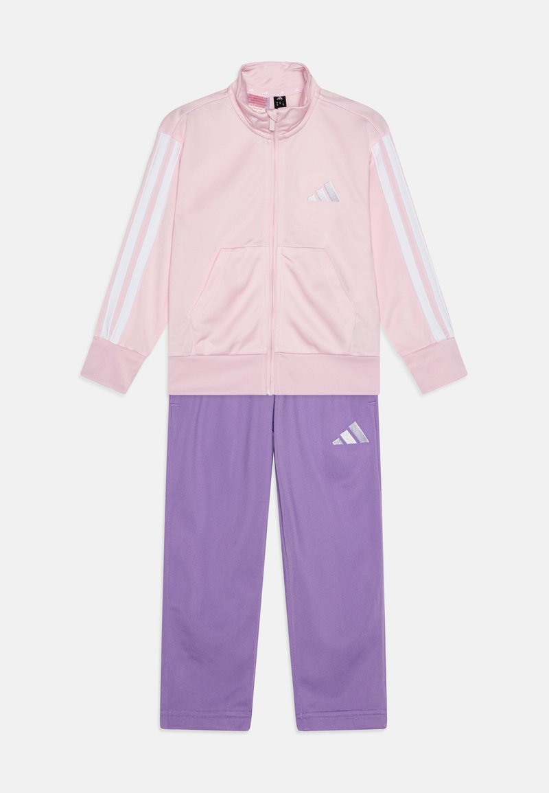 Lyserød zip-up jakke med hvide striber, parret med lilla bukser med et lille logo. Fremstillet af glat, letvægtsstof.